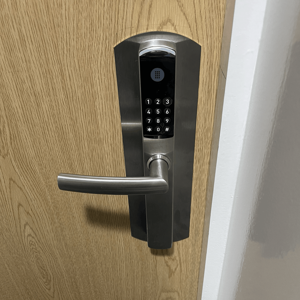 Omnitec os slim code hotel door lock in silver with silver plate on a wooden door by hotel lock and safe
