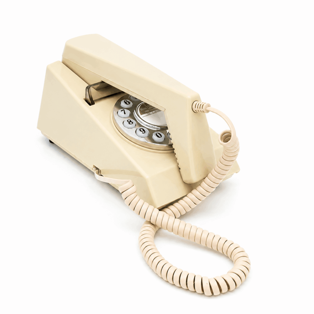 Side view of the GPO Trim push button hotel guest room phone in Ivory on a white background by hotel lock and safe