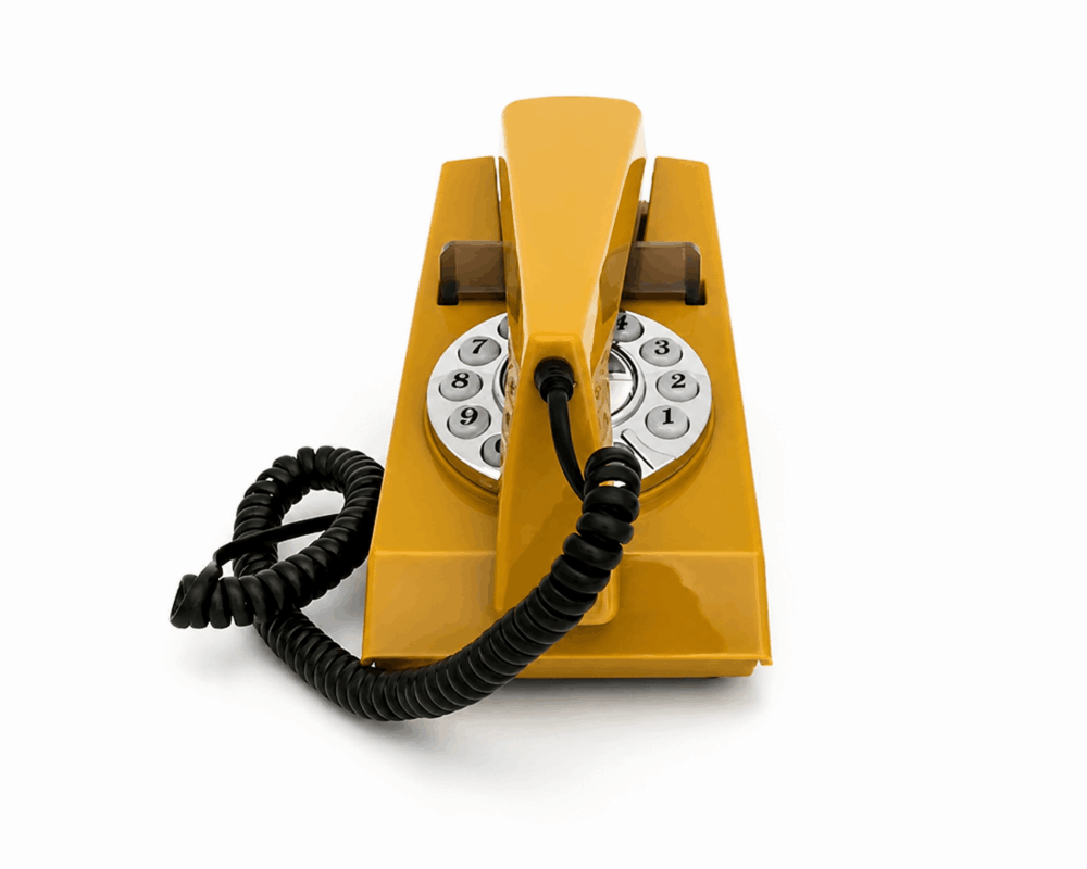 GPO Trim hotel guest room retro push button phone in a mustard colour on a white background showing the front view by hotel lock and safe