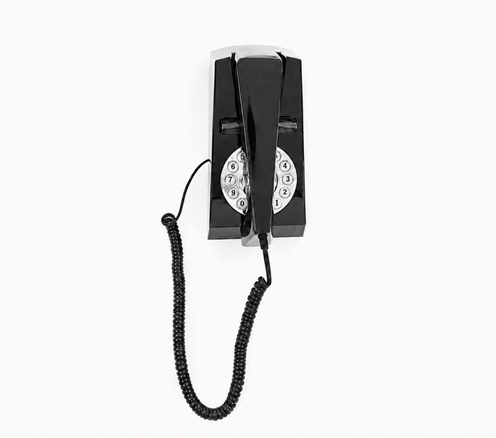 Hotel guest room GPO Trim push button phone in black wall mounted on a white background by hotel lock and safe